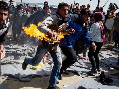 Un refugiado corre este martes tras prenderse fuego durante una protesta en un campamento en la frontera greco-macedonia.
