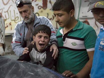 Criança junto ao cadáver de um parente depois do bombardeio em Aleppo.