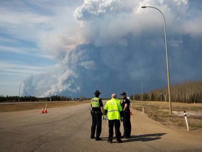 Tres oficiales observan el incendio.