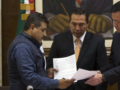 El secretario de Gobernación, a la derecha, intercambia documentos con un representante de la CNTE.