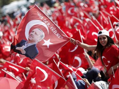 Dois jovens agitam bandeiras da Turquia e com a efígie de Erdogan