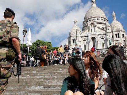 Un militar patrulla junto a un grupo de turistas coreanas, a la entrada del Sacre Coeur de París.