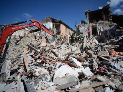 Os bombeiros e as equipes de resgata inspecionam edifícios destruídos em Amatrice.