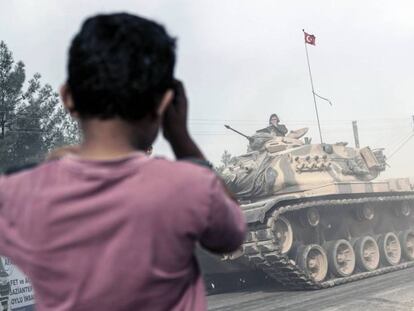 Un niño mira un tanque turco que se dirige a la frontera siria, en la localidad de Karkamis, sureste de Turquía.