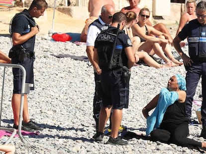 Policiais em Niza obrigam a uma mulher a descobrir na praia.