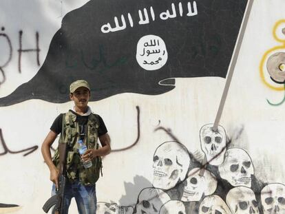 Um miliciano do Exército Sírio Livre, diante de um mural do EI, em Yarablus.