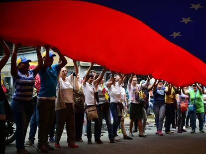 Opositores al chavismo se manifiestan ayer portando una gran bandera venezolana en Los Teques, en el Estado de Miranda. R. SCHEMIDT