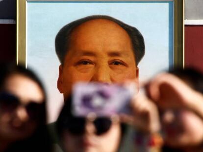 Três mulheres tiram uma foto na frente do retrato de Mao Tse-Tung na praça de Tiananmen em Pequim.