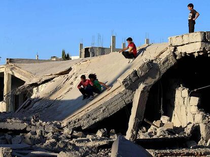 Unos niños se deslizan sobre uno de los edificios destruidos en Daraya, cerca de Damasco.