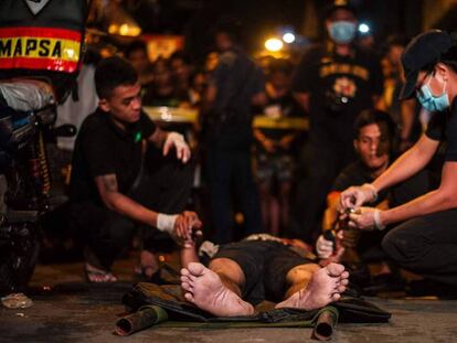 Policías analizan el cadáver de un supuesto drogadicto asesinado en septiembre en Manila.