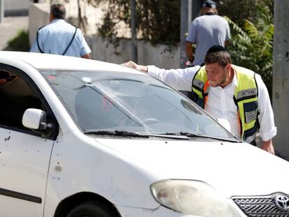 Un trabajador del servicio de emergencias mira dentro del vehículo que utilizó el asaltante.