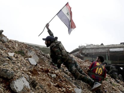 Un soldado sirio coloca una bandera nacional.