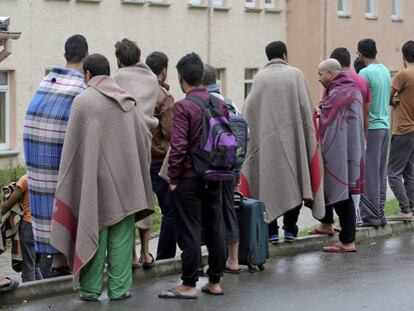 Un grupo de solicitantes de asilo permanece en el exterior de un centro de acogida tras un incendio en la localidad de Aue (Alemania), a mediados de 2015.
