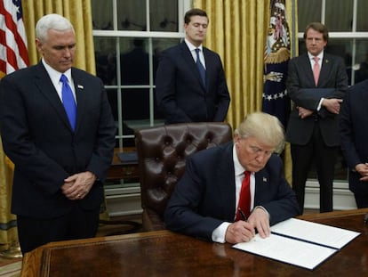 El presidente Donald Trump, en el centro, firmando su primera orden ejecutiva este 20 de enero.