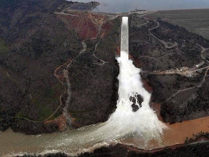 El agua sale al máximo de capacidad por el desagüe de la presa Oroville, el lunes. A la izquierda, el muro de emergencia dañado.
