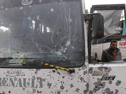 Dos hombres supervisan los destrozos de uno de los autobuses alcanzados en el doble atentado en Damasco.