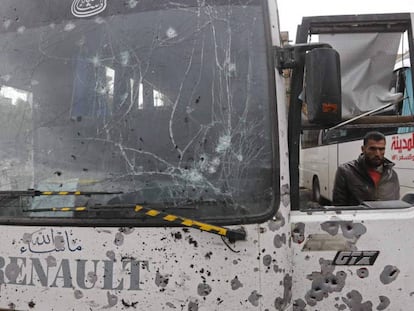 Dos hombres supervisan los destrozos de uno de los autobuses alcanzados en el doble atentado en Damasco.