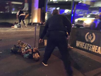 Policías junto a los cuerpos tendidos de dos supuestos terroristas en Londres.