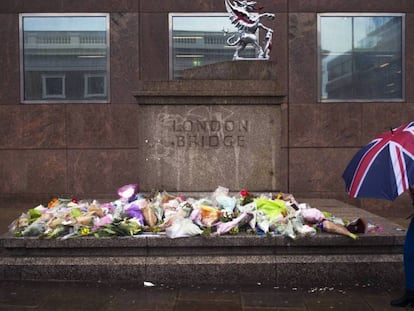 Una mujer pasa delante de varios ramos de flores dejados en memoria de las víctimas del atentado del sábado en el Puente de Londres.