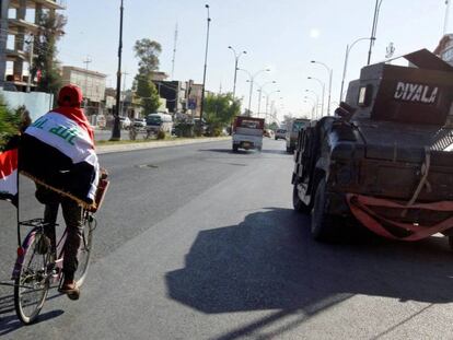 Un hombre envuelto en la bandera de Irak monta en bicicleta por las calles de Kirkuk.