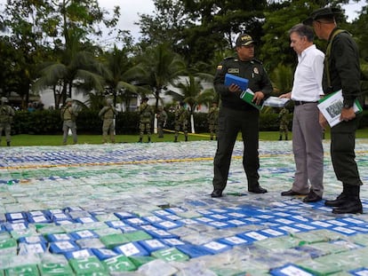 El presidente de Colombia, Juan Manuel Santos, y dos agentes sobre las más de 12 toneladas de cocaína incautada.