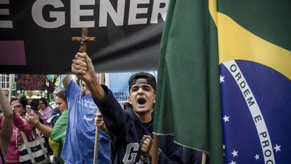 Un joven protesta contra la filósofa feminista Judith Butler, el pasado 9 de noviembre en São Paulo. En vídeo, perfil de Jair Bolsonaro, diputado y candidato presidencial de extrema derecha.
