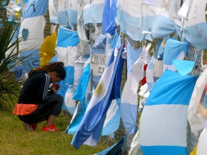 Una mujer se arrodilla ante las banderas que homenajean a los 44 tripulantes del Ara San Juan, en la base naval de Mar del Plata.