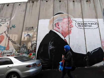 Una mujer camina junto a un graffiti del presidente de EE UU, Donald Trump, en el muro de separación israelí de Belén, este jueves. / Vídeo: Declaraciones del Papa Francisco con respecto a Jerusalén.