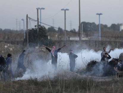 Manifestantes palestinos se ocultan de los gases lacrimógenos lanzados por las tropas israelíes durante los enfrentamientos en la frontera con Gaza, este sábado.