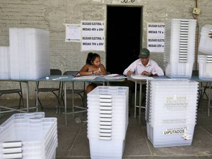 Dos funcionarios preparan las urnas para la segunda vuelta electoral.