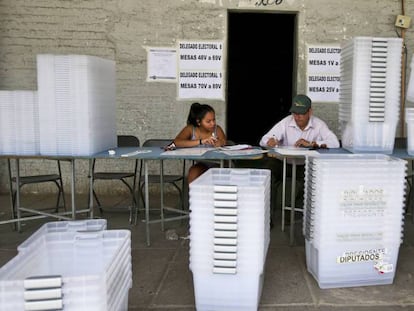 Dos funcionarios preparan las urnas para la segunda vuelta electoral.