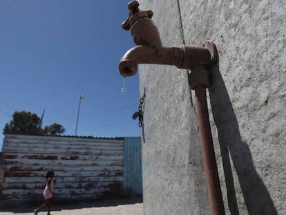 Una joven camina cerca del grifo comunal en el barrio Khayelitsha en Ciudad del Cabo.