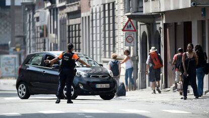 Una policía impide el paso a un vehículo hacia la zona del ataque de hoy en Lieja.