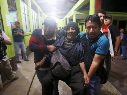 Dos voluntarios ayudan a un hombre a entrar a un albergue.