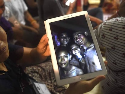 Una familiar muestra una foto de algunos de los desaparecidos tomada dentro de la cueva por los equipos de rescate. En vídeo, las primeras imágenes de los niños.
