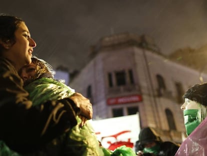 Dos jóvenes favorables al aborto legal se abrazan y lloran bajo la lluvia frente al Congreso argentino.