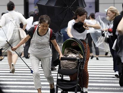 Unos peatones luchan contra los fuertes vientos y la lluvia hoy en Tokio.