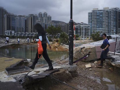 Varias personas caminan entre los destrozos causados ​​por el tifón Mangkhut en el paseo marítimo de Hong Kong.