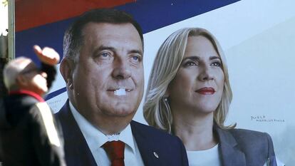 Un hombre, ante un cartel electoral con las imágenes del presidente y la primera ministra serbobosnios, Milorad Dodik y Zeljka Cvijanovic, este viernes en la ciudad bosnia de Banja Luka / En vídeo, declaraciones de Milorad Dodik