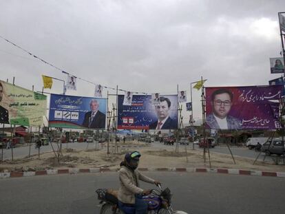 Un motorista frente a carteles de campaña de candidatos parlamentarios, este martes en Kabul / En vídeo, el arranque de los comicios en Afganistán (ATLAS)