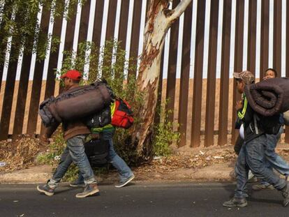 Migrantes caminando en los alrededores del muro fronterizo