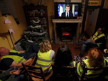 Un grupo de 'chalecos amarillos' sigue el discurso de Emmanuel Macron, este lunes. En vídeo, las protestas de los 'chalecos amarillos' resienten la economía francesa.