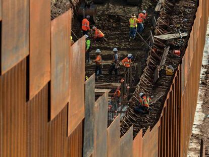 Trabajadores levantando una valla en la frontera de México con Estados Unidos. En vídeo, el anuncio de Trump.