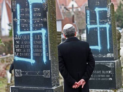 Un hombre contempla las lápidas vandalizadas de varios judíos en el cementerio de Quatzenheim (Francia), el 19 de febrero de 2019. / En vídeo: Declaraciones del presidente de Francia, Emmanuel Macron.
