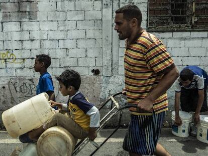 En la foto, un hombre y sus hijos portan garrafas de agua en Caracas. En el vídeo, declaraciones de Nicolás Maduro.