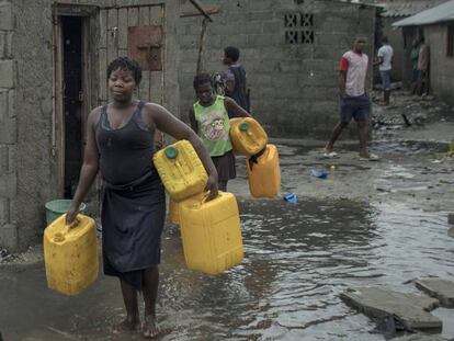 Varias personas cargan bidones para buscar agua en Praia Nova Village, un barrio en Beira, Mozambique. En vídeo, crisis humanitaria en Mozambique.