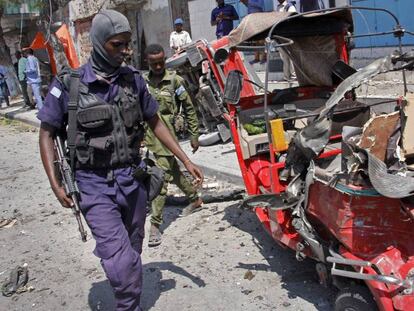 Un policía junto a un vehículo destrozado en el atentado en Mogadiscio.