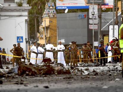 Unos sacerdotes observan los restos de una furgoneta bomba hoy lunes en Colombo (Sri Lanka). / En vídeo: nuevas imágenes del atentado de Sri Lanka.