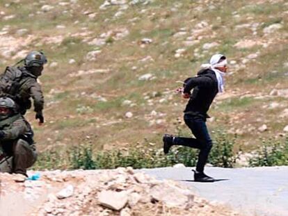 El joven palestino Osama Hajajra huye maniatado de tropas israelíes, el jueves en Cisjordania, antes de ser herido.