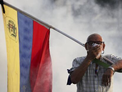 Un hombre se protege del gas lacrimógeno durante la protesta de esta mañana.